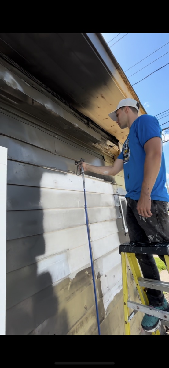 Brush Buds crew member priming exterior siding
